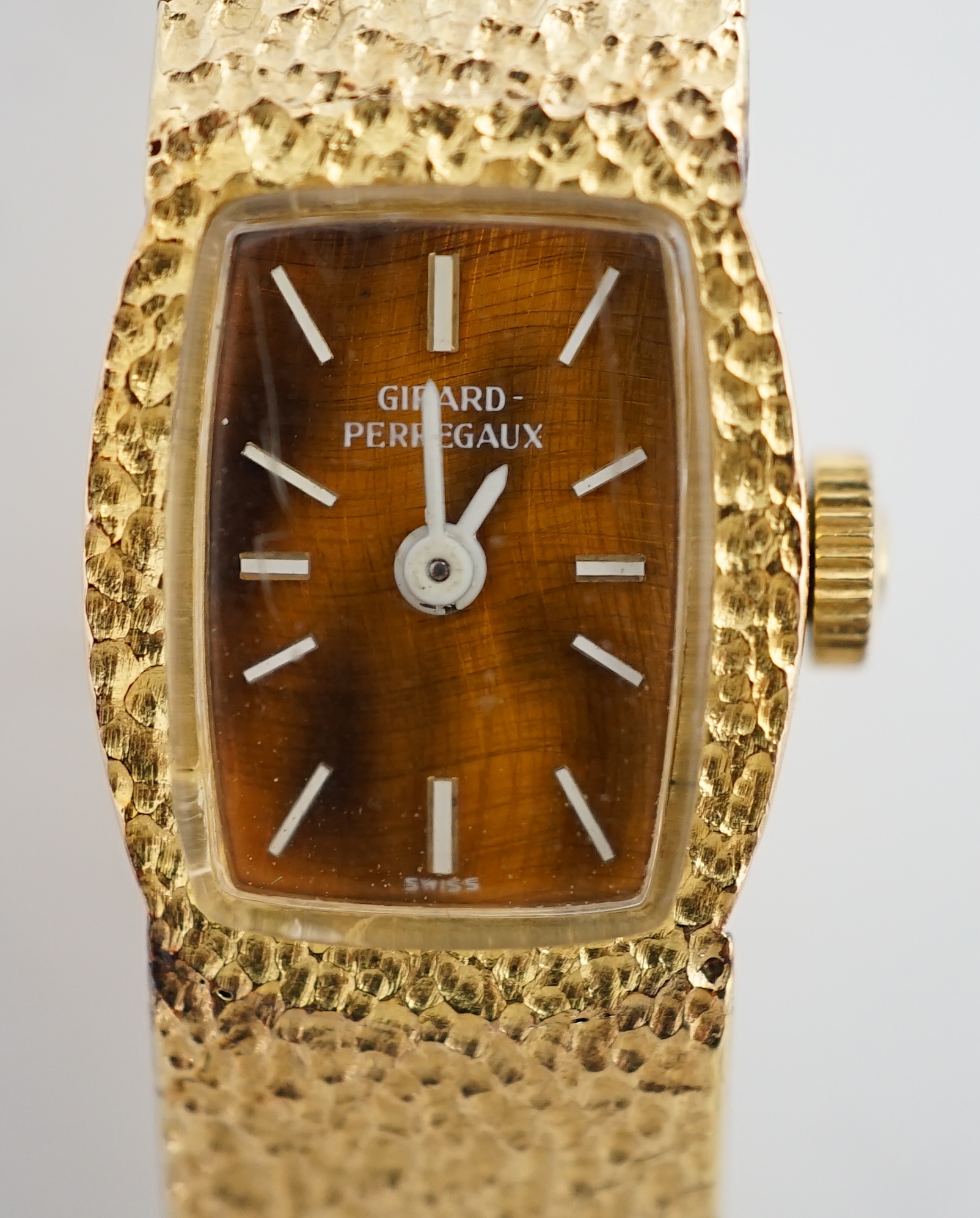 A lady's Girard Perregaux 18K yellow gold wrist watch, with tiger's eye quartz dial, white hands and markers, on integral textured close-link flexible bracelet with clasp